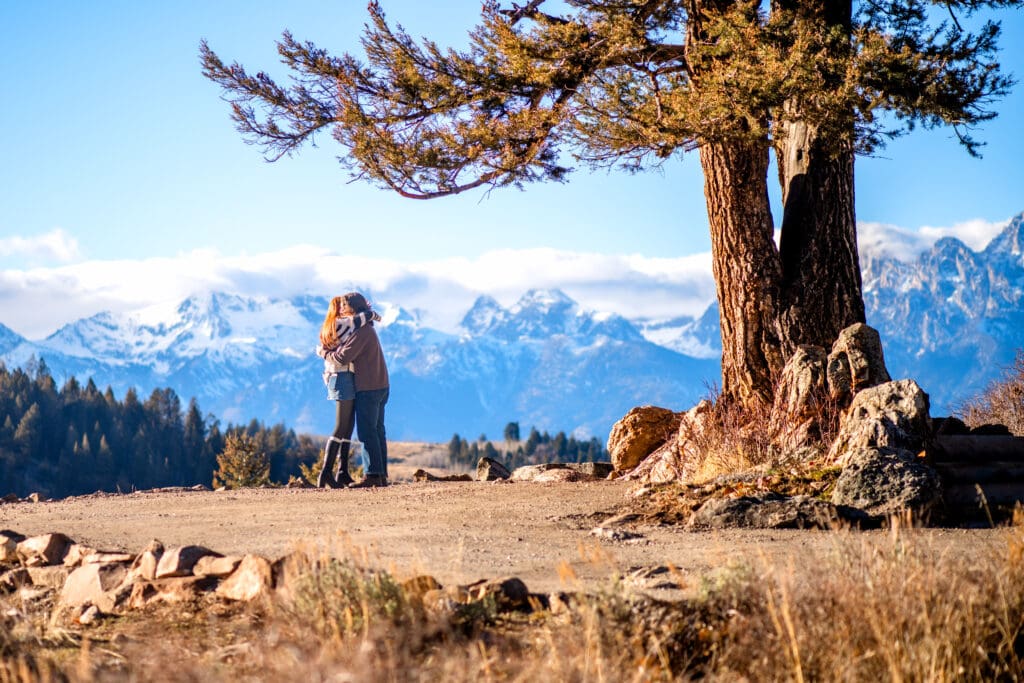 Couple kissing in front of a view of the Grand Tetons.