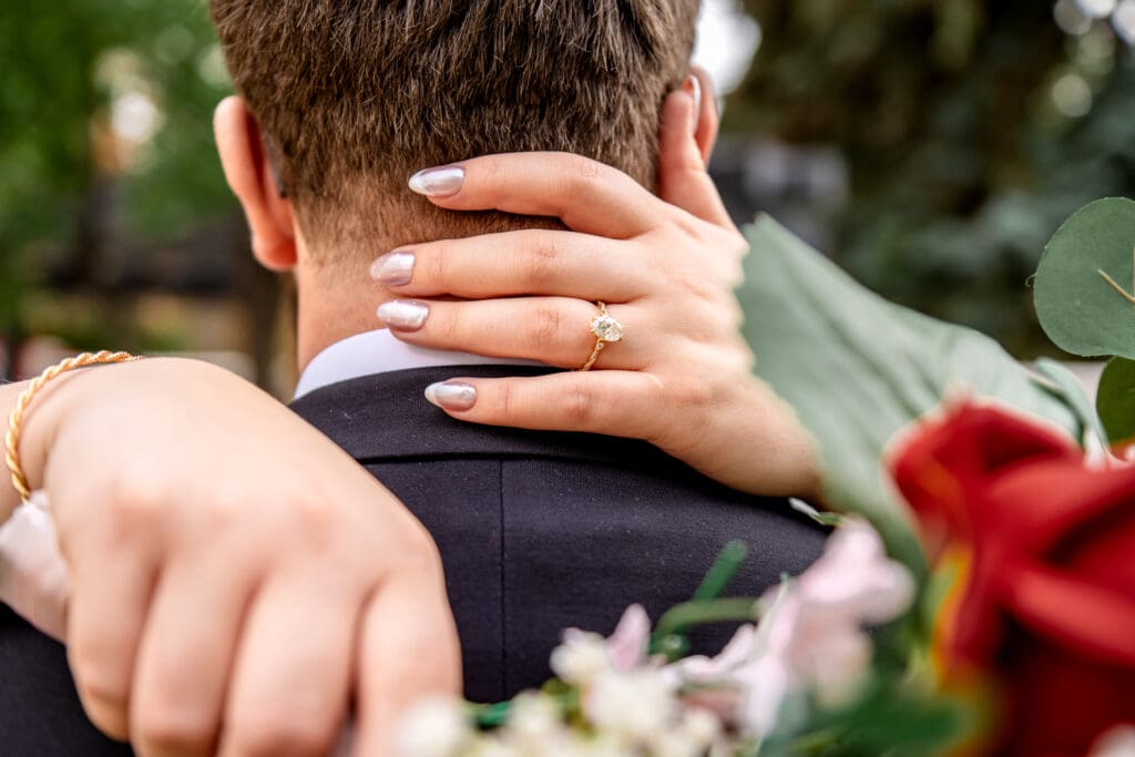 Beautiful wedding ring on bride's hands cupping the back of groom's neck.