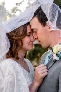 Bride and groom touching noses and foreheads with eyes closed under veil in Idaho Falls.
