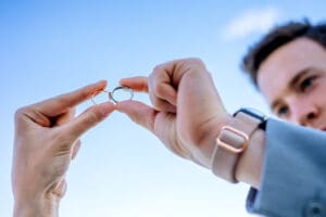 Bride and groom's wedding bands touching each other as hands hold it up to the sky in Idaho Falls.