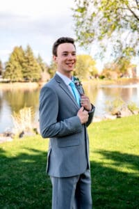 Groom standing confidently and smiling to the distance with hands on suit collar in Idaho Falls.