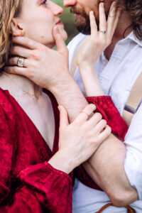 Man and woman each place a hand on the other's jaw, showcasing jewelry as woman places other hand on man's arm, captured by Utah engagement photographer.