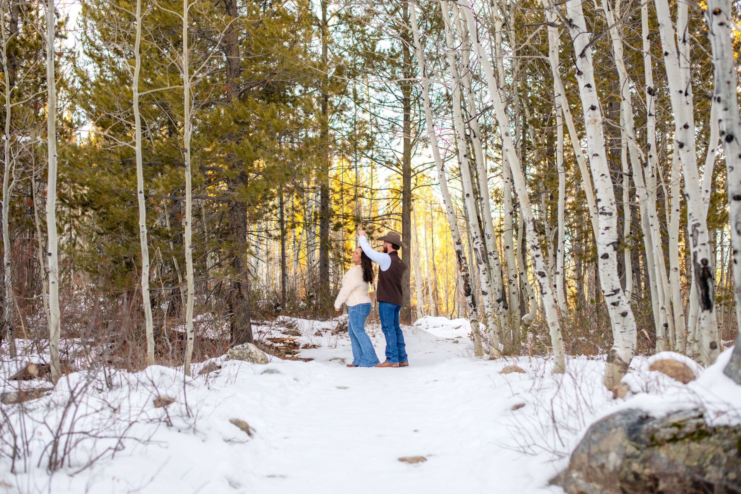 Husband spins wife in wintery landscape framed by aspens, taken by Grand Teton National Park photographer.