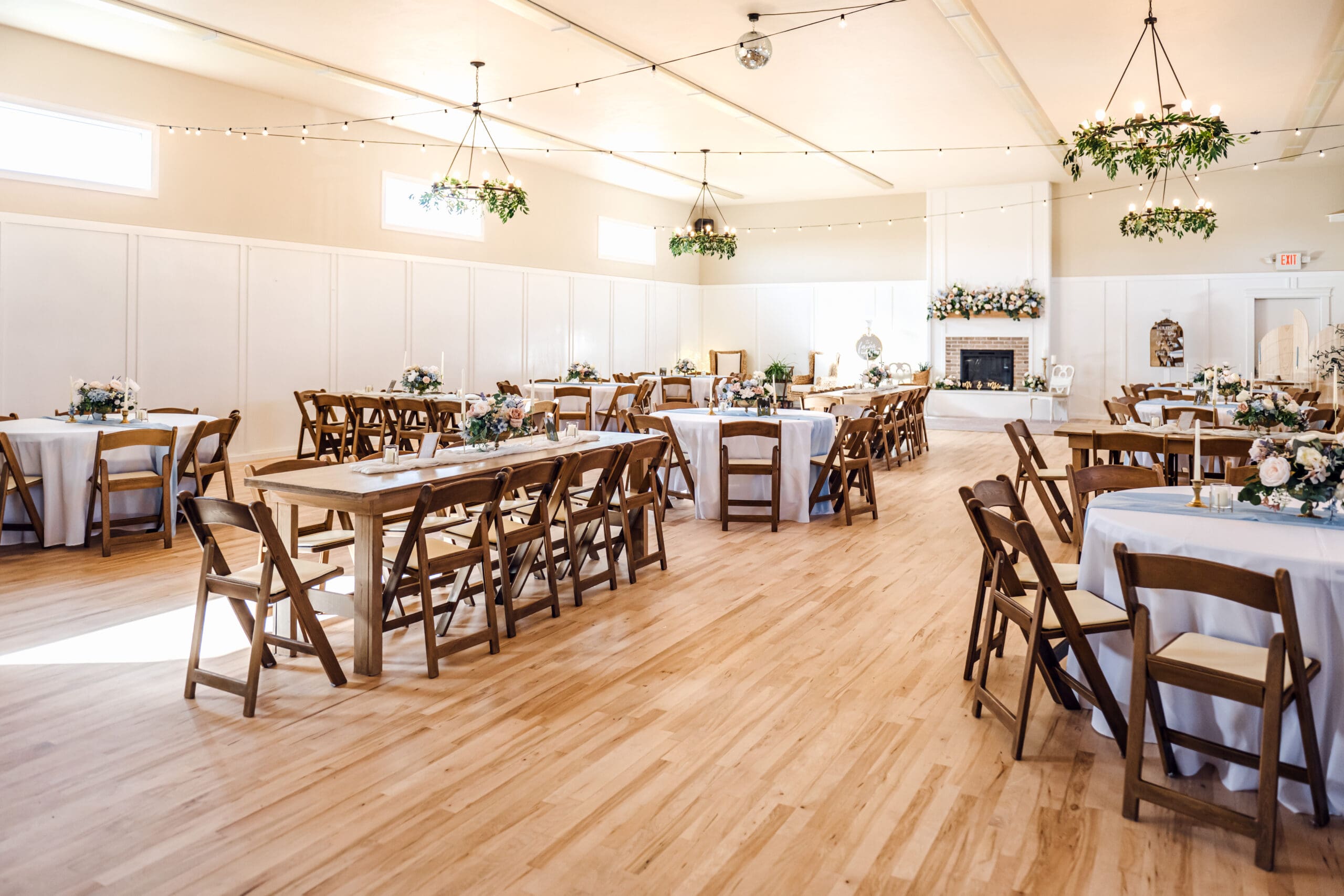 The Aisle in Sugar City, a wedding venue, with light coming through windows and set up for receptions with dark wood tables, florals, and light linens, captured by Rexburg wedding photographer.