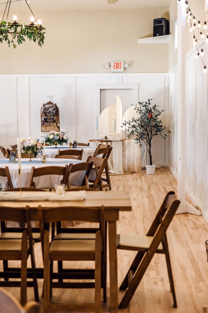 Dark wood tables with linens and decor and chandeliers at The Aisle wedding venue in Sugar City, captured by Rexburg wedding photographer.